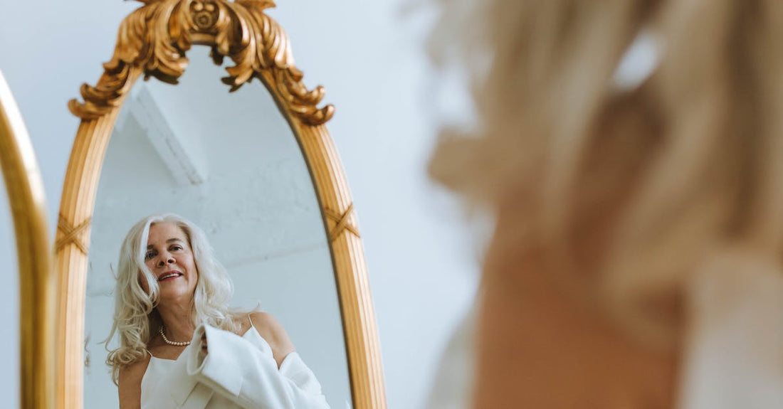 Happy Elderly Woman in White Clothing looking at a Mirror