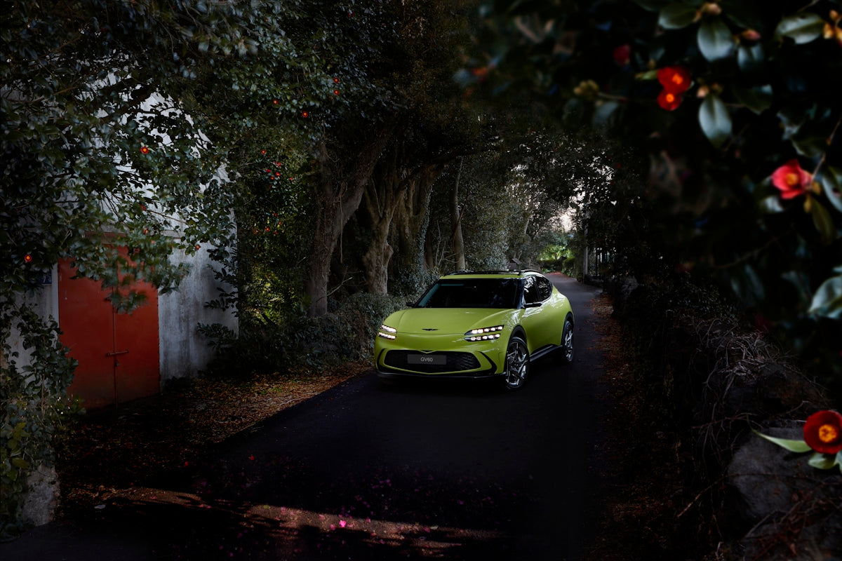 a green car driving down a dark street