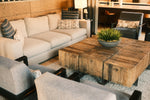 Modern living room with sectional sofa and rustic coffee table.