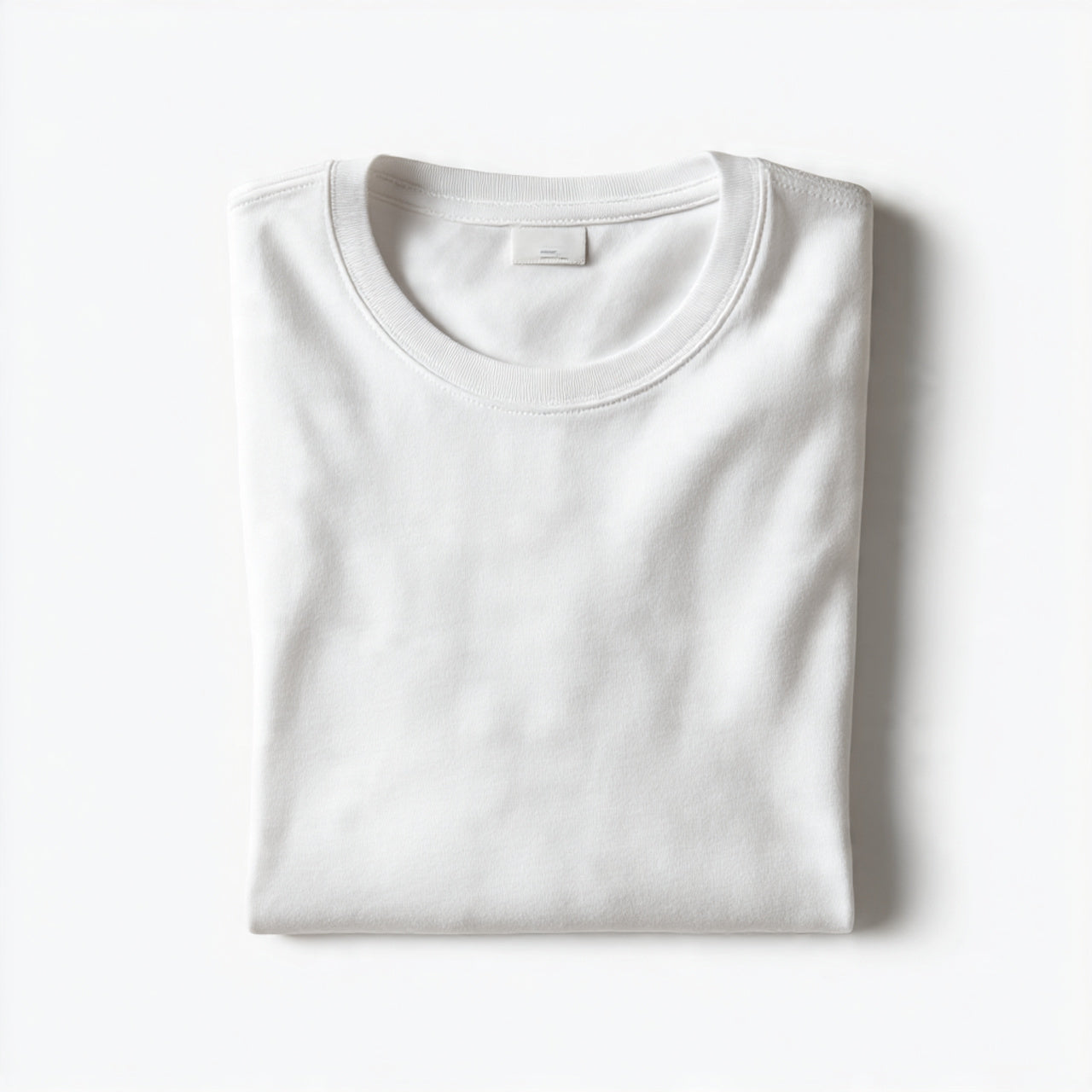 “A folded men’s T-shirt centered on a pure white seamless background. Straight-on high-end studio photography with soft shadow. No text, no logo, no model, no props.”
