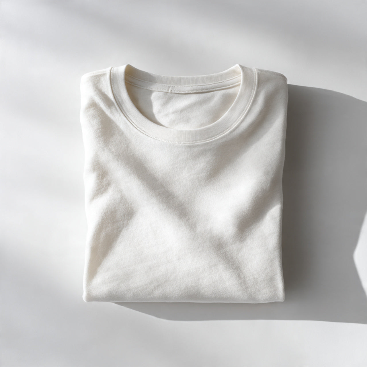 “A folded organic cotton garment centered on a pure white seamless background. Straight-on premium product shot with soft natural lighting and minimal shadow. No text, no logo, no model, no props.”