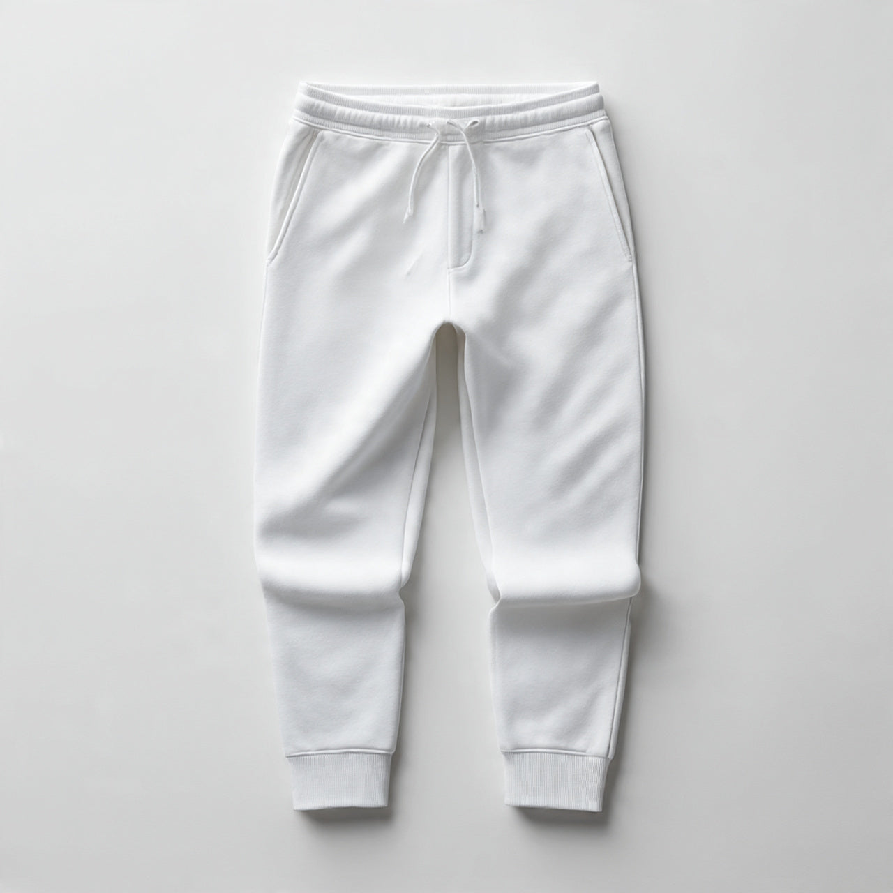 “A folded pair of men’s sweatpants centered on a pure white seamless background. Straight-on premium product shot with soft lighting and minimal shadow. No text, no logo, no model, no props.”