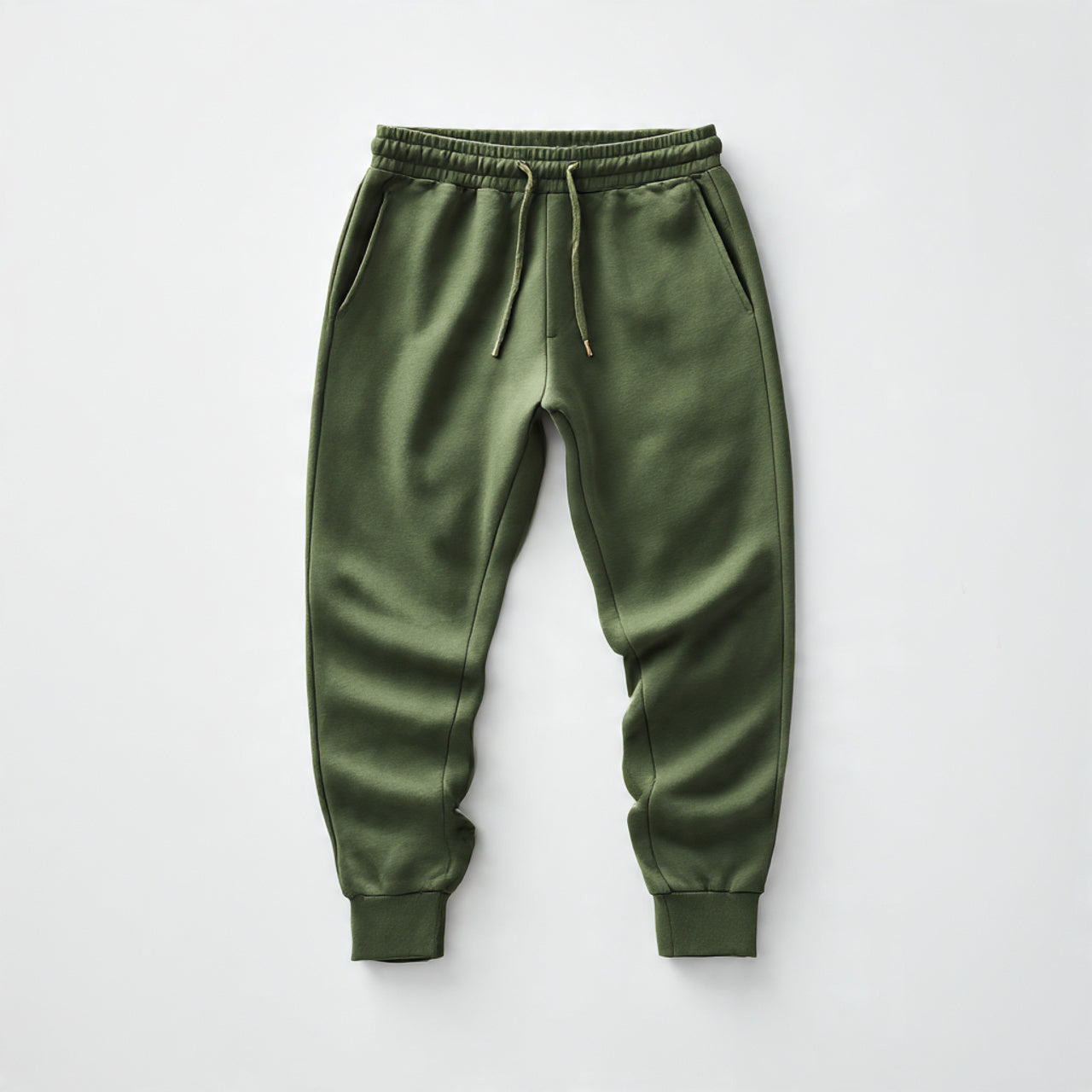 “A neatly folded pair of men’s joggers centered on a pure white seamless background. Straight-on studio lighting with a soft shadow. No text, no logo, no model, no props.”