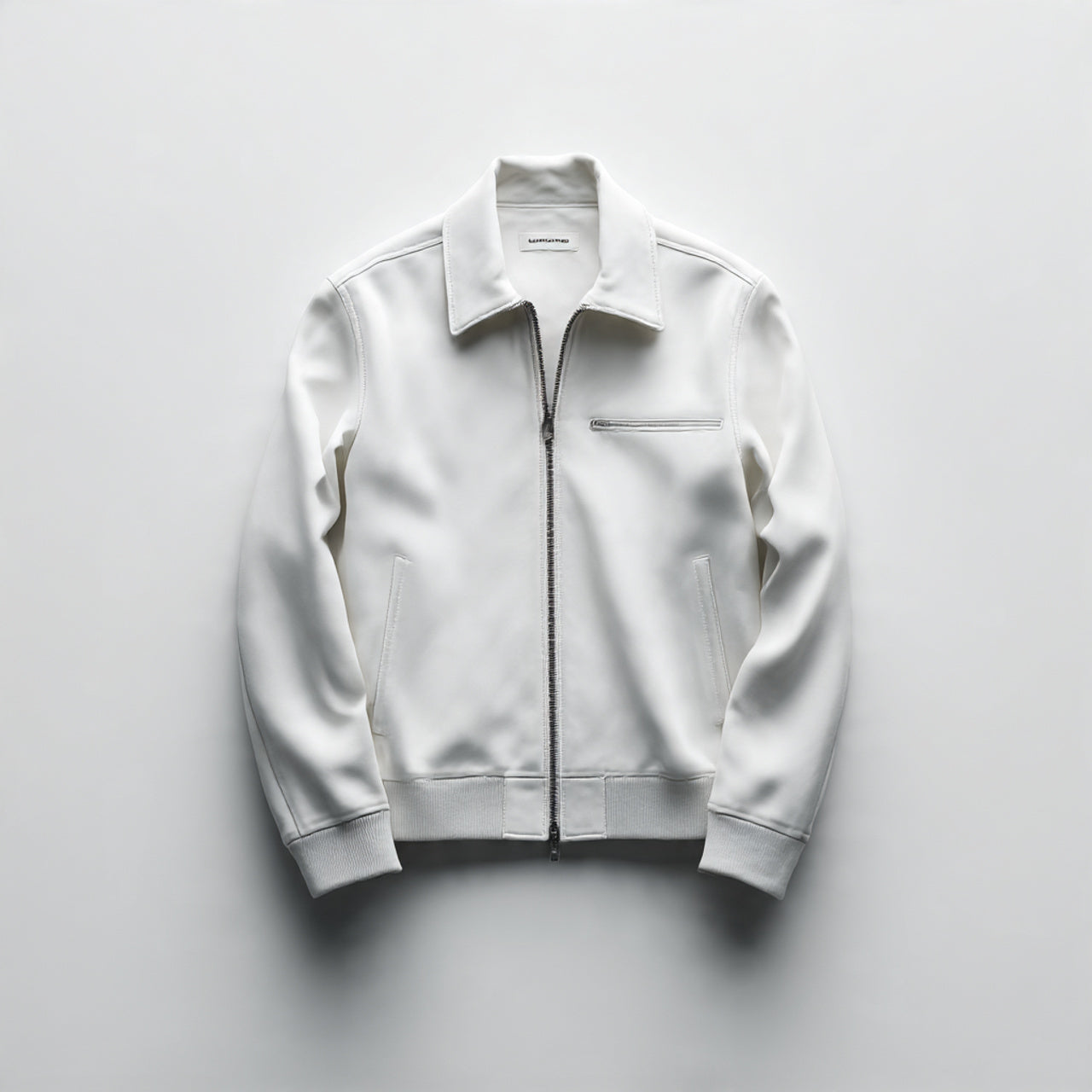 “A single men’s jacket centered on a pure white seamless background. Straight-on high-end product shot with clean studio lighting and a soft shadow under the jacket. Minimal, luxury presentation. No text, no logo, no model, no props.”