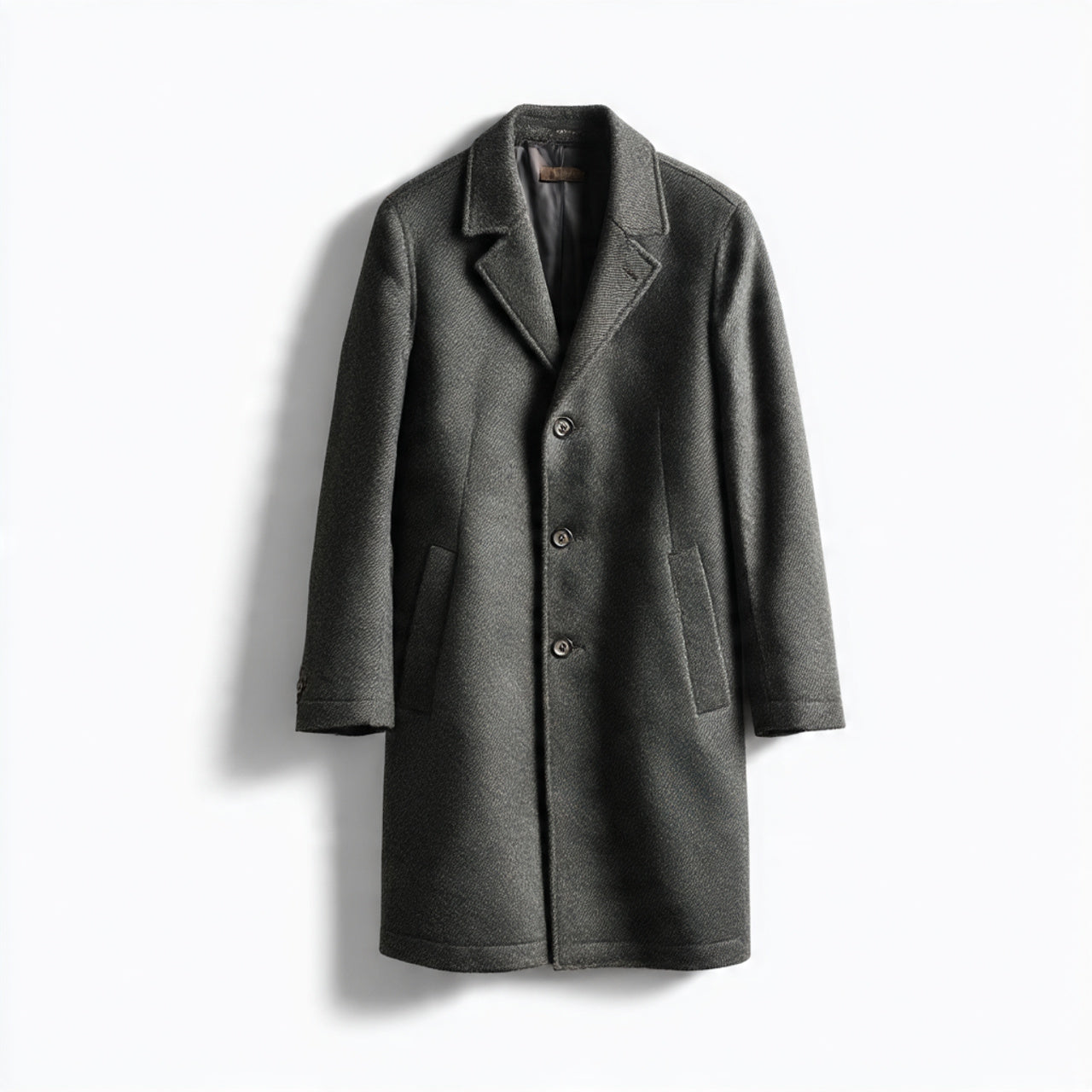 “A single men’s overcoat or long coat displayed on a pure white seamless background. Straight-on premium studio shot with soft lighting and a subtle natural shadow. High-quality product photography. No text, no logo, no model, no props.”