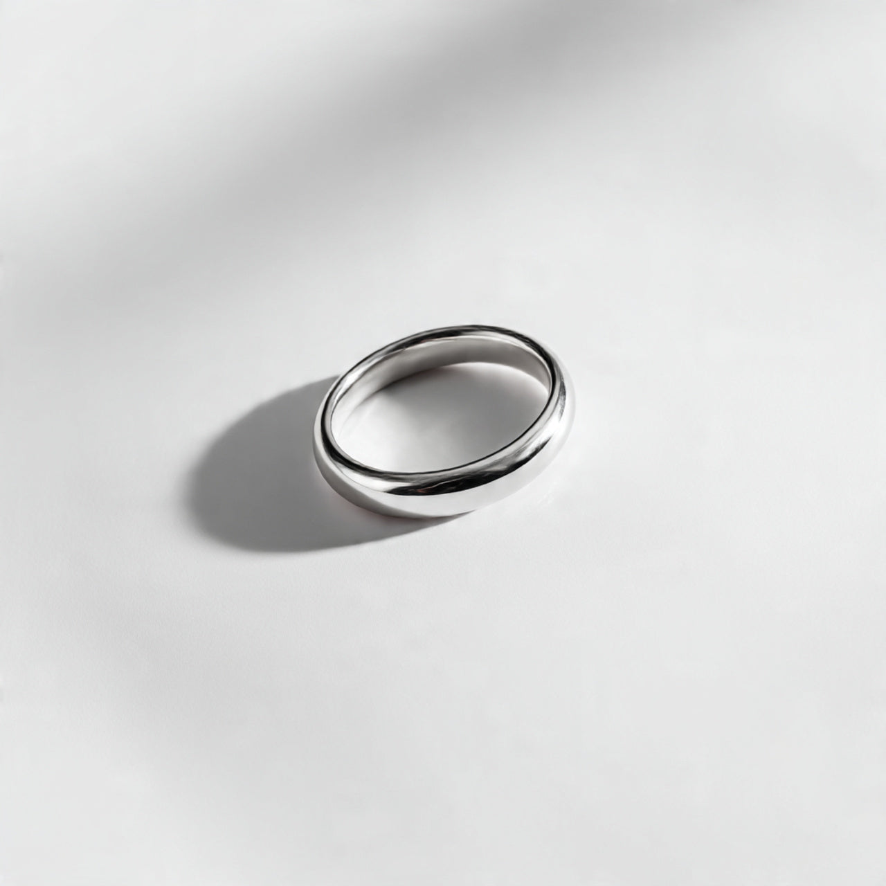 “A single minimalist ring centered on a pure white seamless background. Straight-on jewelry product photography with soft diffused lighting and a small shadow. No text, no logo, no model, no props.”