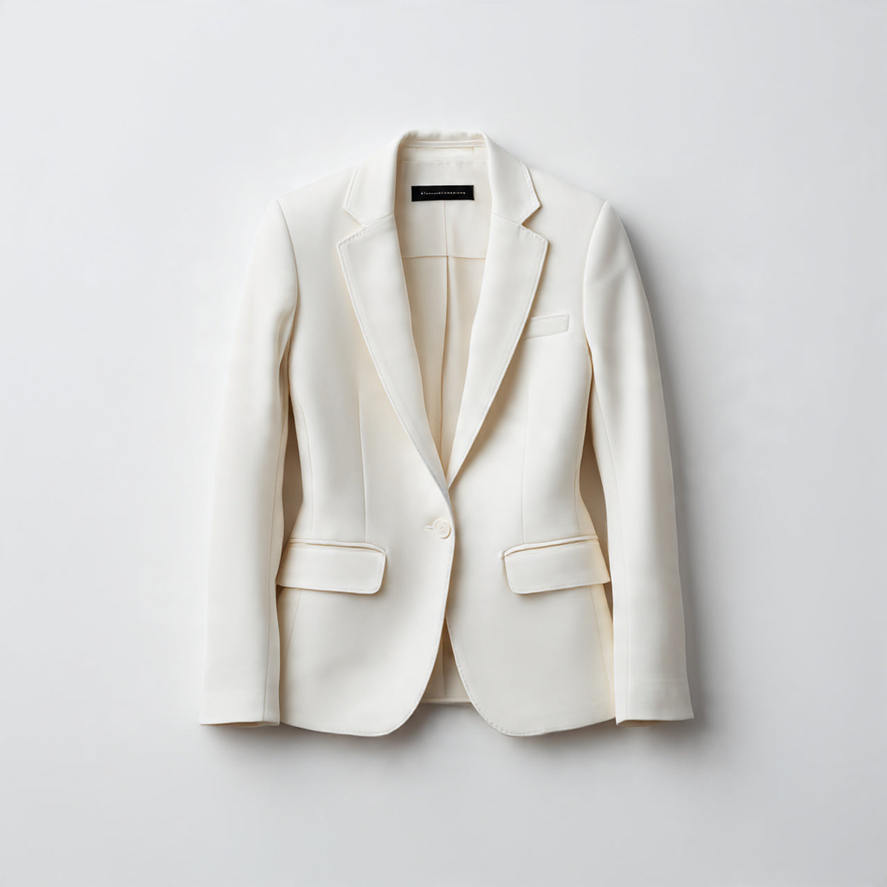 “A single women's blazer centered on a pure white seamless background. Straight-on luxury product photography with soft studio lighting and a clean natural shadow. No text, no logo, no model, no props.”