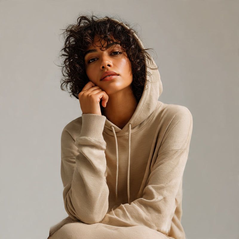 Woman wearing a beige hoodie against a plain background