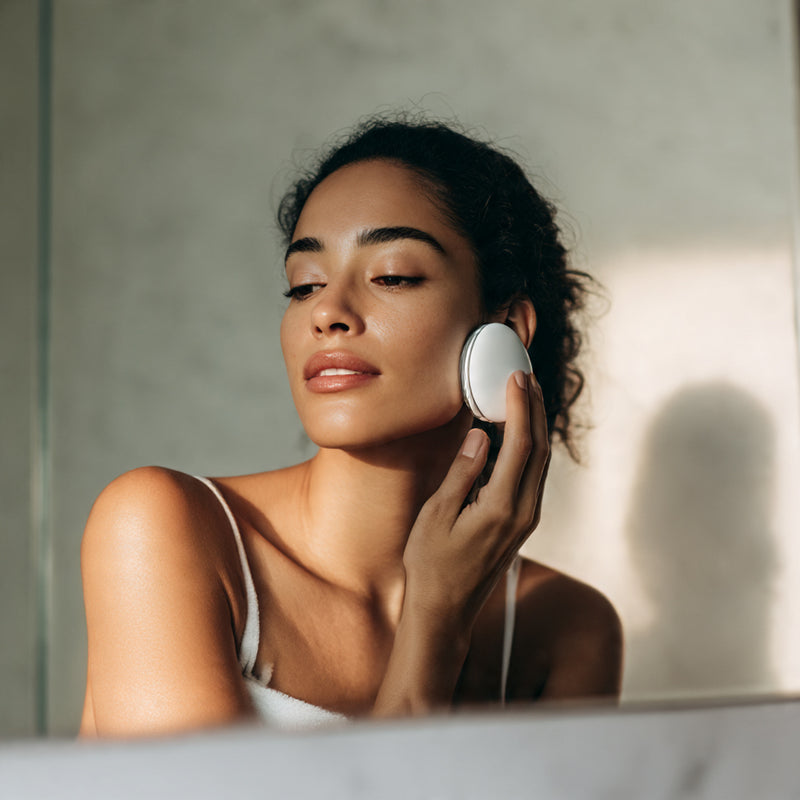 Woman applying a facial product to her face in a bathroom setting